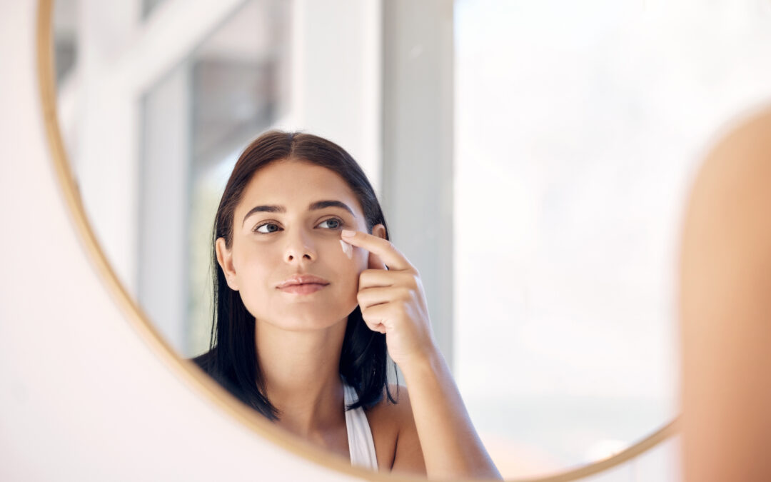 Woman applying eye cream in mirror